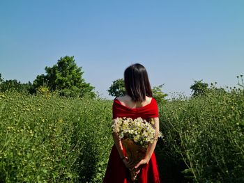 Rear view of woman standing on field against clear sky