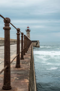 Lighthouse by sea against sky
