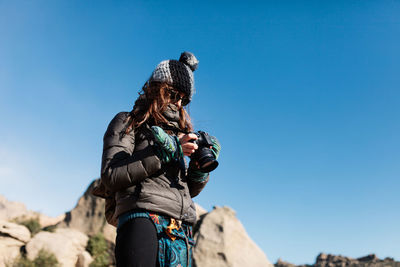 Low angle view of person holding rock against blue sky