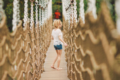 Rear view of woman walking on footbridge