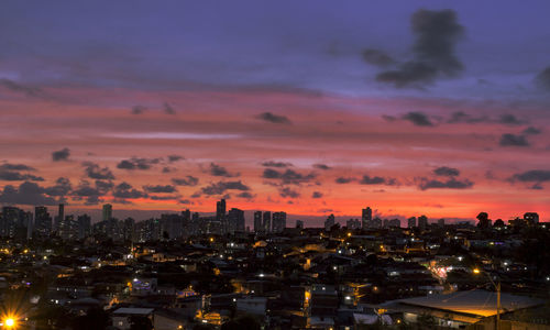 Illuminated cityscape against sky during sunset