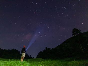 Woman standing on field against sky at night