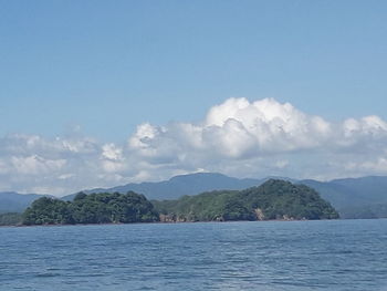 Scenic view of sea by mountains against sky