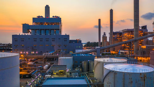 Illuminated factory against sky at sunset