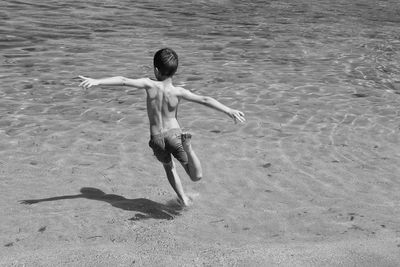 Rear view of shirtless boy running at beach