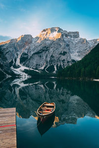 Boat moored at lake against rocky mountains