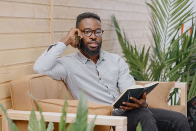 African american in an office or coworking talking on the phone and taking notes in a notebook