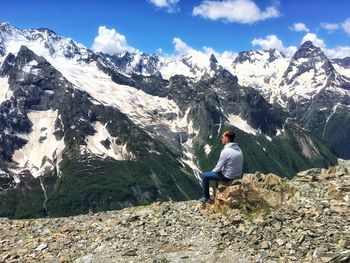 Rear view of man sitting on rock