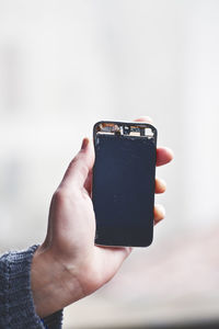 Cropped hand of woman holding broken mobile phone