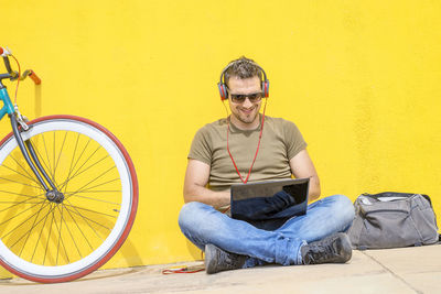 Portrait of young man sitting against wall