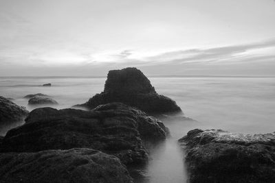 Scenic view of rocks in sea against sky