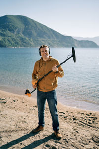 Full length of man holding umbrella while standing at beach