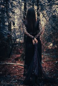 Woman standing by tree in forest