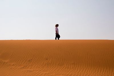 Woman standing on sand dune at desert