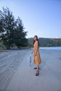 Full length of young woman standing against sky