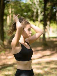 Side view of teenage girl tying hair while exercising in park