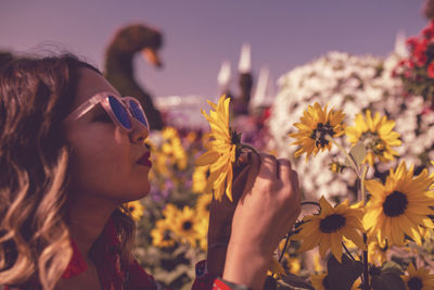 Close-up of young woman holding flower in ornamental garden at dusk