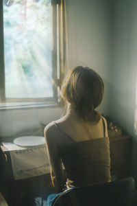 Rear view of girl sitting at home