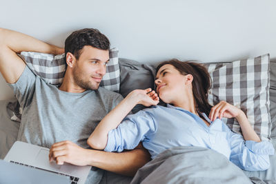 High angle view of couple lying on bed at home