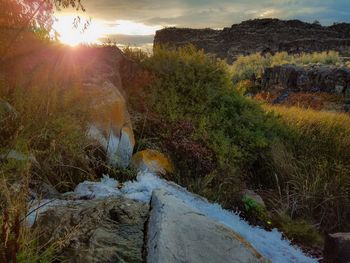 Scenic view of waterfall against sky during sunset