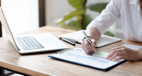 Midsection of person using laptop on table