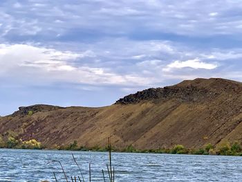 Scenic view of lake by mountains against sky