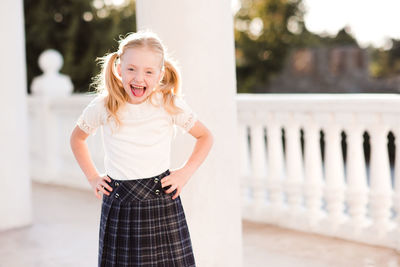 Portrait of cute girl standing against column