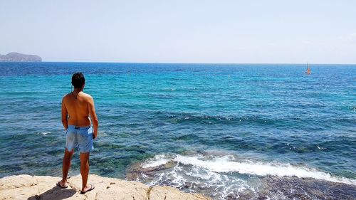 Rear view of man looking at sea against sky