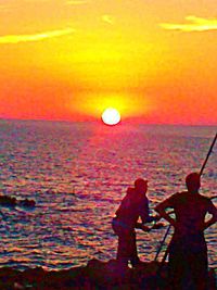 Silhouette people against sea during sunset