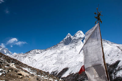 Low angle view of prayer flag by snowcapped mountains against sky