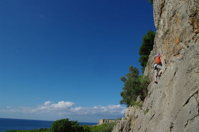 Low angle view of woman climbing on cliff