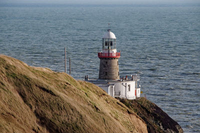 Lighthouse by sea against building