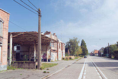 Road by buildings against sky