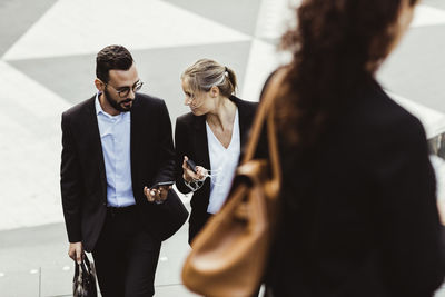 High angle view of female and male entrepreneurs talking while walking outdoors