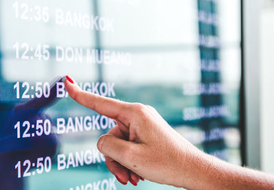 Cropped hand checking arrival departure board at airport