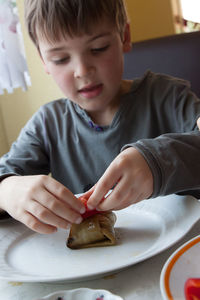 Boy preparing beef kebab in kitchen