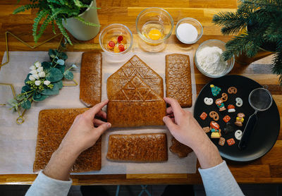 High angle view of person preparing christmas gingerbread house on kitchen counter