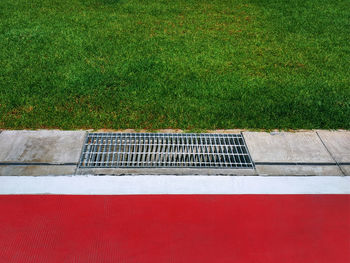 Metal grating by red floor and green grass field