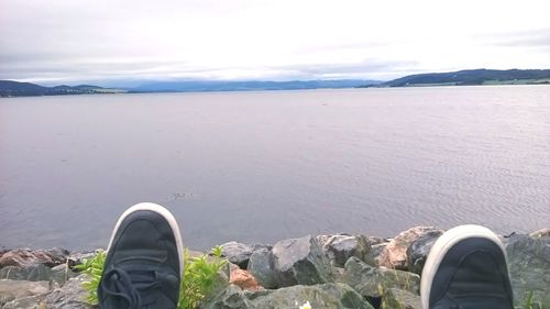 Low angle view of people standing on rocks at lakeshore