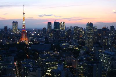 Illuminated cityscape against sky at sunset