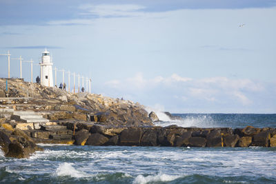 Lighthouse by sea against sky