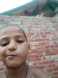 Portrait of boy looking at brick wall