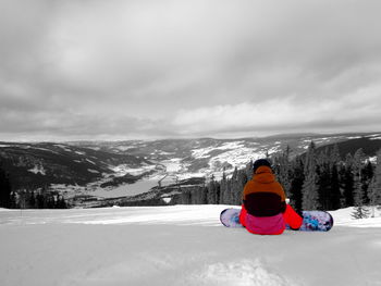 Rear view of person on snowcapped mountain against sky