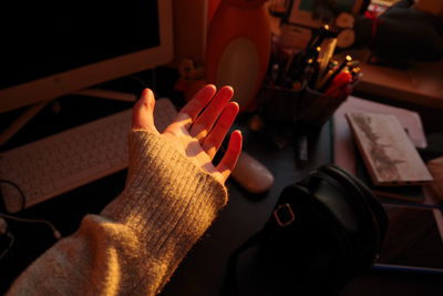 Cropped hand of woman gesturing at desk during sunset