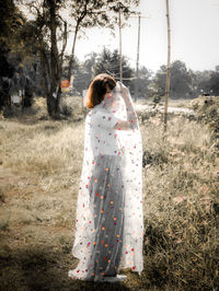 Rear view of woman standing on field