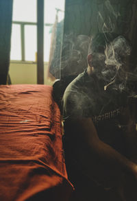 Close-up of man smoking cigarette at home