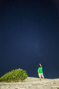 Rear view of man on field pointing at star field