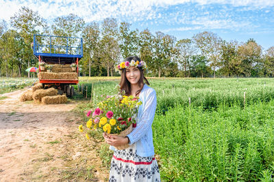 Woman holding flower while standing on field