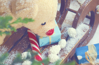 Teddy bear on snow covered wooden sledge