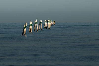 Wooden posts in sea against sky